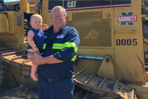 Joe Volpert-holding Michael Garrett next to a company bulldozer